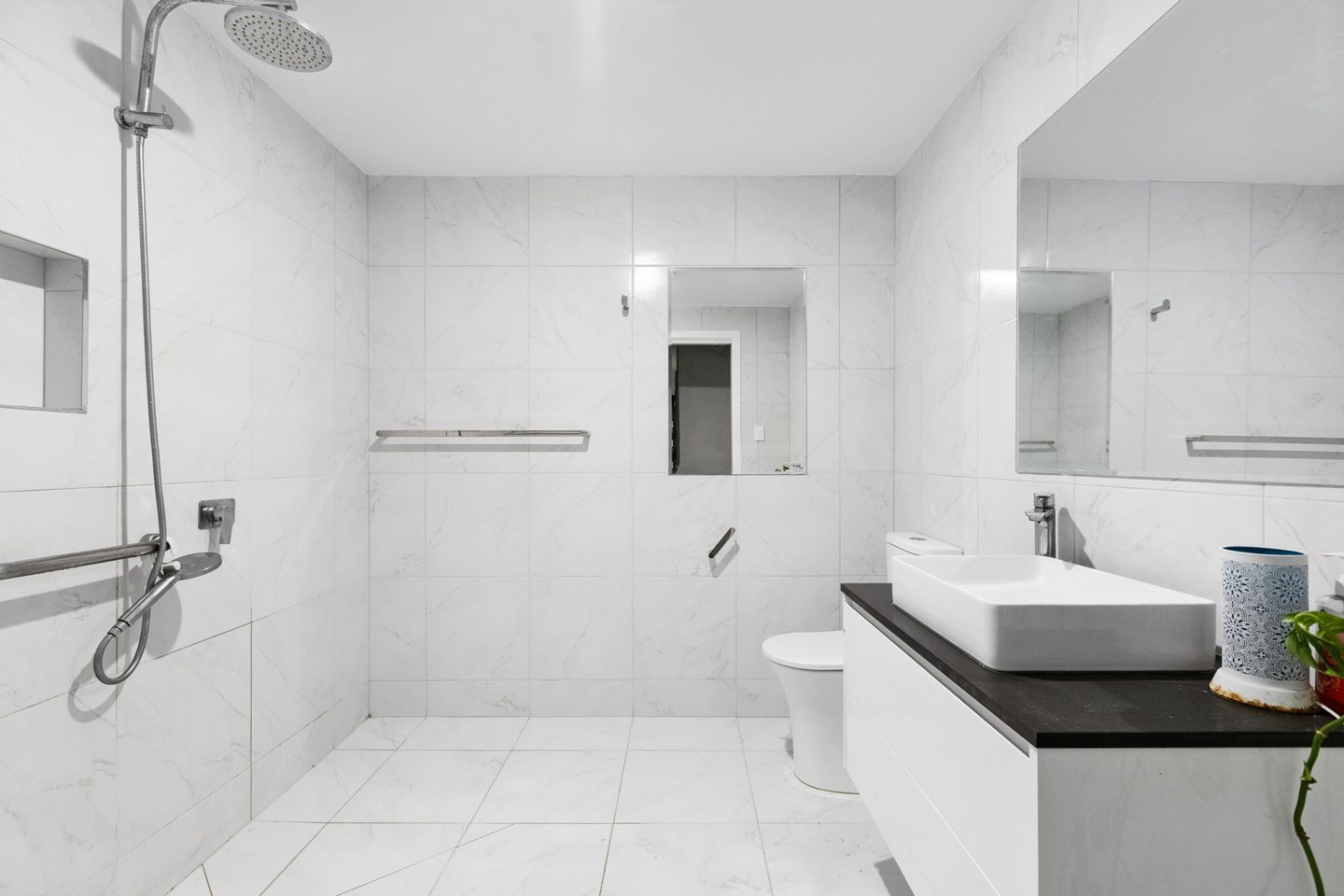 Tiled bathroom with an open shower and vanity
