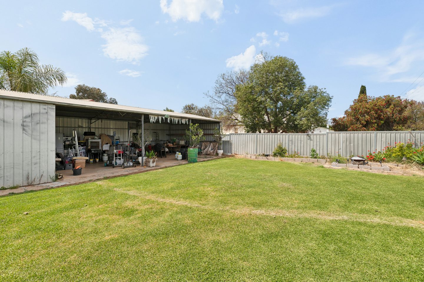 Wide backyard with shedding and perimeter garden beds